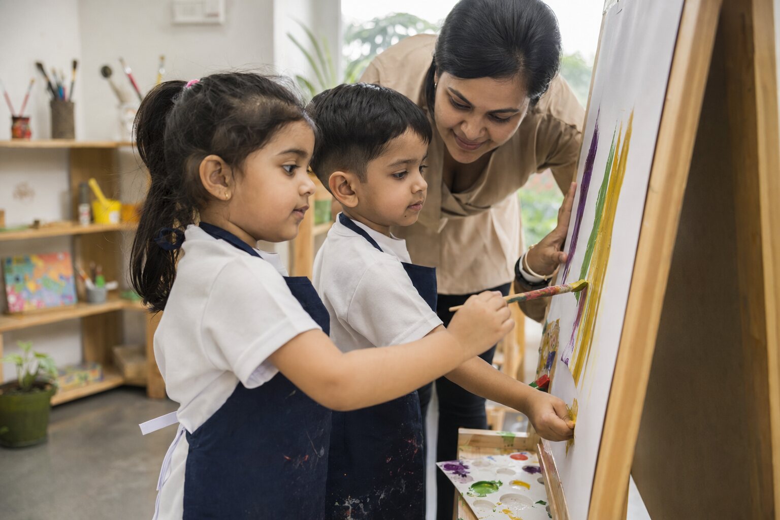 Children painting with a teacher in an Arkley classroom